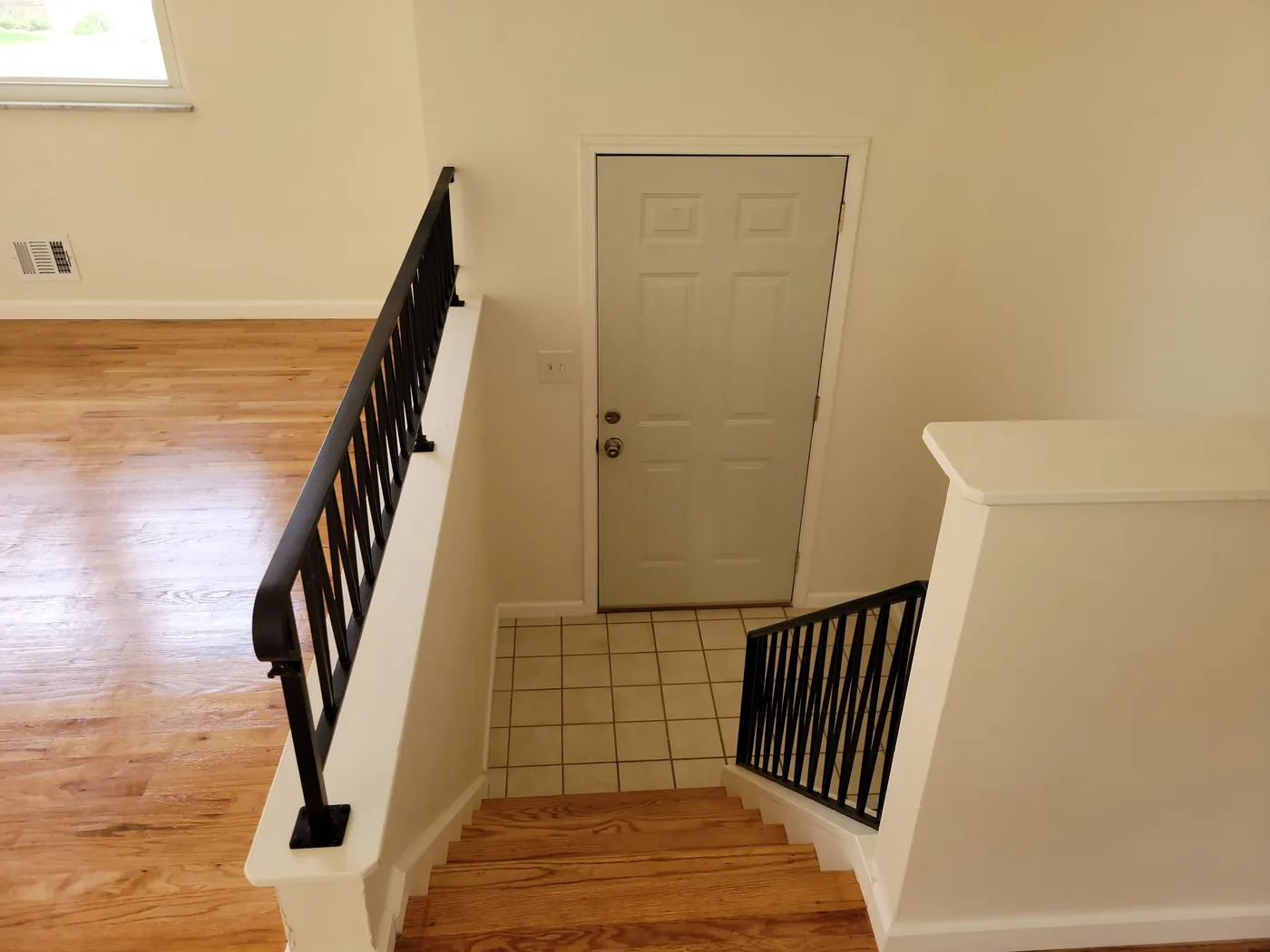 Entry staircase with hardwood floor and black railing