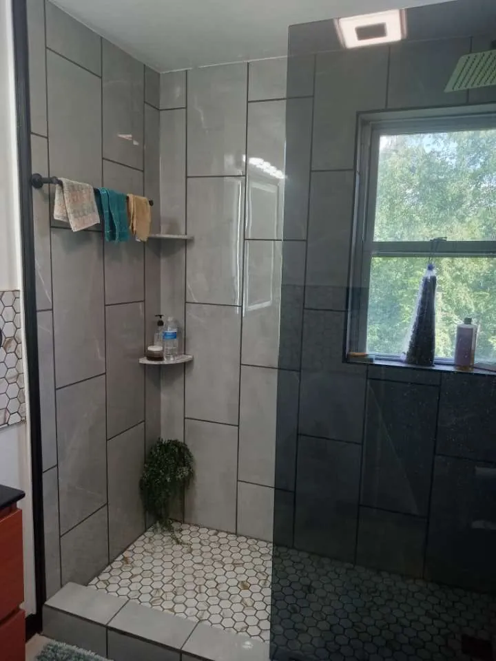 Walk in shower with large grey tile and a hex tile floor